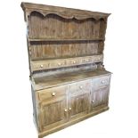 A VICTORIAN STYLE LIMED PINE DRESSER With open shelves above an arrangement of drawers and