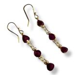 A PAIR OF YELLOW METAL AND RUBY EARRINGS Each set with three pear cut stones. (tests as 14ct, approx