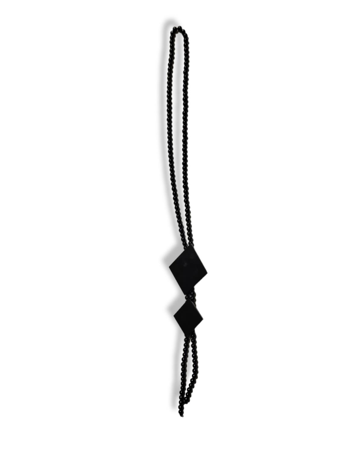 AN ART DECO DESIGN CARVED JET NECKLACE Having a strand of spherical beads with two diamond form