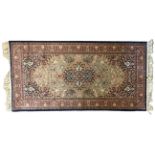 A PERSIAN KASHAN WOOLLEN RUG Having scrolled floral decoration to central olive green field with