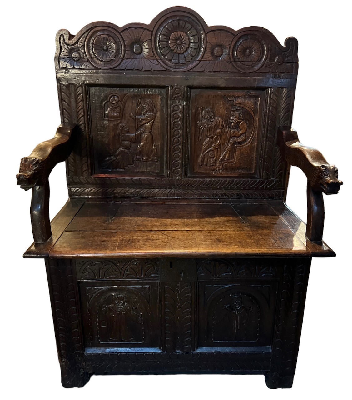 AN 18TH CENTURY CARVED COFFER CONVERTED TO A SETTLE With four pictorial panels and hinged lid. (h