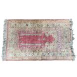 A TURKISH PRAYER RUG On a pink ground with stylised floral borders. (86cm x 127cm)