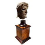 AFTER THE ANTIQUE, A DECORATIVE BRONZED PLASTER HEAD OF ZEUS Raised on a walnut plinth base. (h 33cm