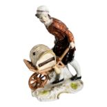 A 19TH CENTURY PORCELAIN FIGURE OF A MERCHANT HOLDING A WHEELBARROW. (possibly Furstenberg). (h 13.