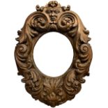 A 19TH CENTURY CONTINENTAL OVAL FRAME CARVED WITH FACIAL MASK AND SCROLLING FOLIAGE. (rebate 32cm