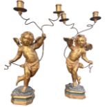 A PAIR OF 18TH CENTURY ITALIAN CARVED GILTWOOD AND PAINTED WINGED CHERUB CANDELABRA Standing on a