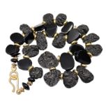 A BLACK TEKTITE AND GILT NECKLACE. (length 44.5cm)