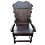 A 17TH CENTURY CARVED OAK WAINSCOT ARMCHAIR The panel back carved with stylised leaves above a plank