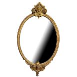 A 19TH CENTURY GILTWOOD AND GESSO OVAL MIRROR With central facial mask, scrolling foliage decoration