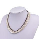 A FOUR STRAND WHITE AND BLACK PEARL NECKLACE HAVING SILVER CLASP Indistinctly signed. (length 43.