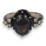 A 14CT WHITE GOLD, BLACK STAR SAPPHIRE AND DIAMOND RING The central cabochon black star sapphire