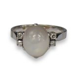 A WHITE METAL, DIAMOND AND WHITE STAR SAPPHIRE RING (TESTED AS 18CT) The central cabochon white star