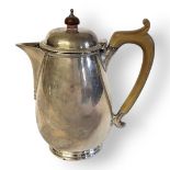 AN EARLY 20TH CENTURY SILVER HOT WATER JUG Carved wooden handle and finial and bulbous body,