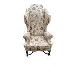 A WILLIAM AND MARY STYLE WING ARMCHAIR With scroll back and arms, shaped apron, upholstered in a