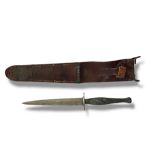A VINTAGE COMMANDO FIGHTING KNIFE Having a textured metal handle and steel blade, in a brown leather