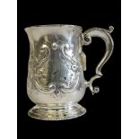 A KING GEORGE II SILVER TANKARD Having a single carry handle and embossed scrolled decoration,