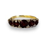 AN EARLY 20TH CENTURY 18CT GOLD GARNET AND DIAMOND RING Five graduated round cut garnets