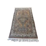 A PERSIAN WOOLLEN RUG Woven with a champagne vase and flowers to central field with two prancing