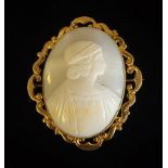 A 19TH CENTURY YELLOW METAL AND SHELL CAMEO BROOCH Carved with a classical female figure in scrolled
