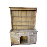 A VICTORIAN PINE DRESSER With open shelves above three drawers and cupboards centred with a dog