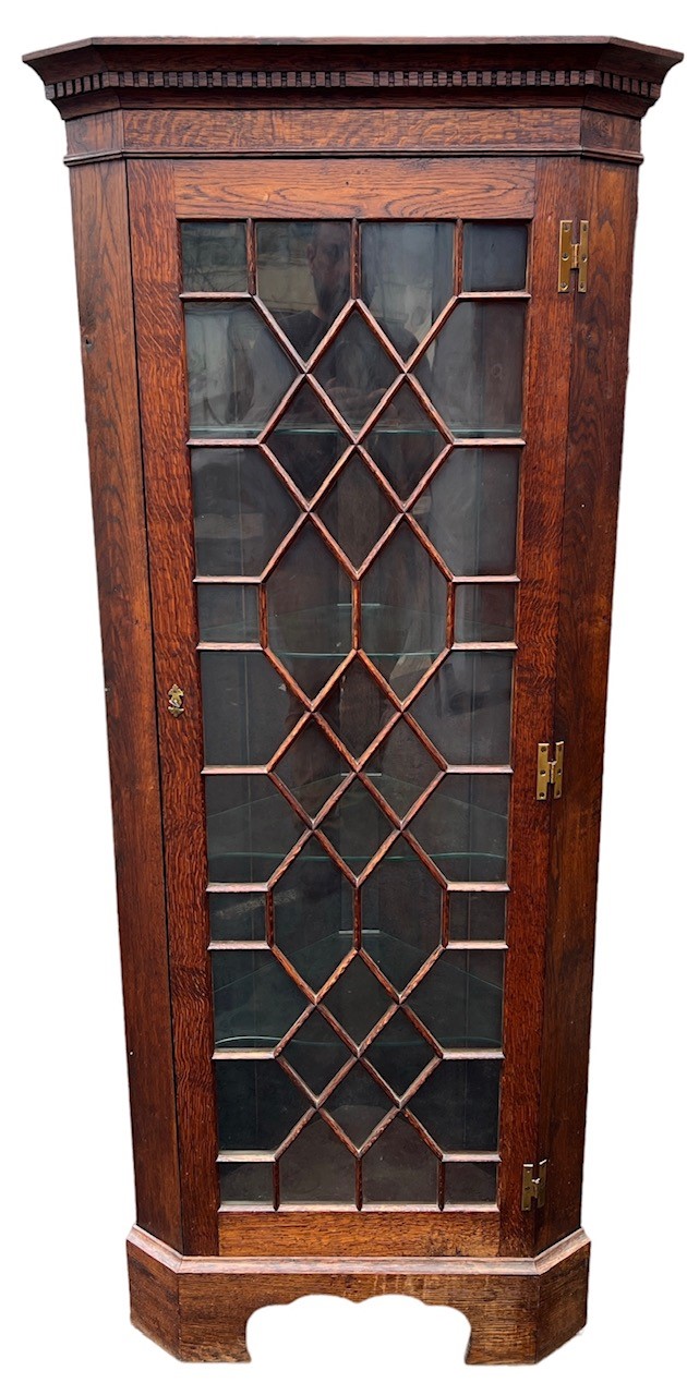 A 20TH CENTURY GEORGE III DESIGN OAK FLOORSTANDING CORNER CABINET With a single aster glazed door