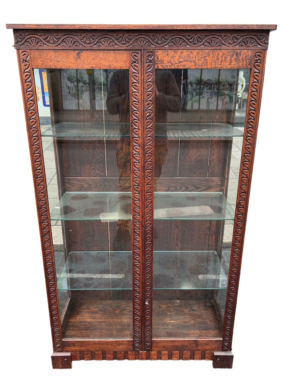 A 20TH CENTURY JACOBEAN DESIGN CARVED OAK DISPLAY CABINET With glazed doors opening to reveal