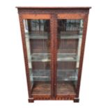 A 20TH CENTURY JACOBEAN DESIGN CARVED OAK DISPLAY CABINET With glazed doors opening to reveal