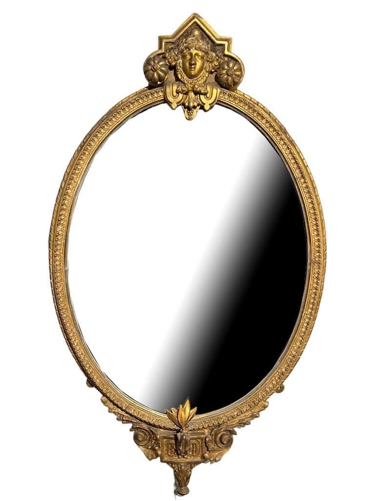 A 19TH CENTURY GILTWOOD AND GESSO OVAL MIRROR With central facial mask, scrolling foliage decoration