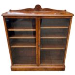 A 19TH CENTURY VICTORIAN FIGURED WALNUT FLOORSTANDING BOOKCASE With a pair of glazed doors opening