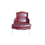 A FRENCH LOUIS XVI DESIGN CARVED WOOD AND PAINTED RED LEATHER WINGBACK ARMCHAIR The shaped back