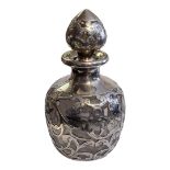 A CONTINENTAL SILVER AND GLASS SCENT BOTTLE Having pierced and scrolled overlaid silver decoration