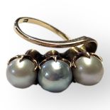 A VINTAGE 14CT GOLD AND PEARL RING Having a row of three pearls in a half twist design. (size M/N)