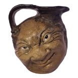 AN EARLY 20TH CENTURY MARTIN BROTHERS STYLE STONEWARE EWER Moulded with grotesque smiling figure,