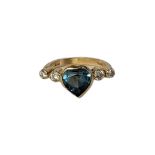AN 18CT GOLD, DIAMOND AND BLUE TOPAZ RING The central heart cut stone flanked with diamonds. (