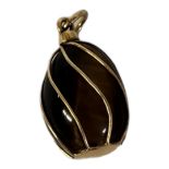 A CONTINENTAL YELLOW METAL AND TIGER'S EYE PENDANT Pear cut stone with yellow metal cage. (approx