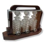 BACCARAT, FRANCE, AN ATTRACTIVE LATE ART DECO TEAK AND SILVER PLATED TANTALUS Containing three