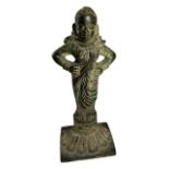 A 17TH CENTURY INDIAN BRONZE FEMALE FIGURE (POSSIBLY PARVATI) With hands on her hips, raised on a
