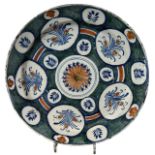 AN 18TH CENTURY DELFTWARE TIN GLAZED CHARGER Decorated in green, orange and blue, central