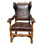 AN UNUSUAL 18TH CENTURY SWISS CARVED OAK AND LEATHER WINGBACK ARMCHAIR With scrolling arms, raised