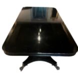 A LARGE BLACK LACQUERED REGENCY DESIGN PEDESTAL DINING TABLE Raised on a quadripartite base