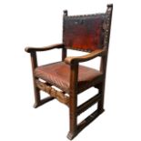 A 19TH CENTURY CARVED WALNUT AND STUDDED LEATHER THRONE CHAIR with scrolling arms.