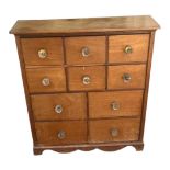 AN EDWARDIAN OAK TABLE TOP CHEST With an arrangement of ten drawers with glass knob handles. (68cm x