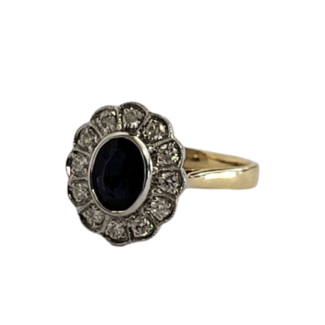 AN 18ct GOLD ,SAPPHIRE AND DIAMOND CLUSTER RING, an oval cut sapphire edged with round cut diamonds.