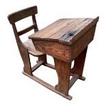 A 19TH CENTURY PINE AND ELM SCHOOL DESK With incorporated chair and sliding top. (56cm x 78cm x