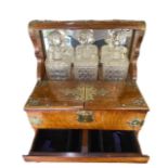 A VICTORIAN WOODEN AND BRASS TANTALUS SET Having three decanters and three port glasses. (h 31.5cm x