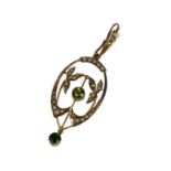 AN EDWARDIAN 9CT GOLD, PERIDOT AND SEED PEARL PENDANT In the shape of a stylised oval with chased