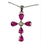 A 9CT WHITE GOLD, PEAR SHAPED RUBY AND DIAMOND CROSS, on a silver chain, boxed. (Approx.Rubies 2.