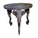 AN EARLY 20TH CENTURY CARVED INDIAN TEAK OCCASIONAL TABLE The circular top raised three elephants