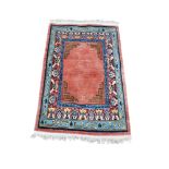 A PERSIAN DESIGN WOOLLEN RUG With geometric border on a salmon pink ground. (100cm x 150cm)