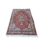 A VINTAGE WOOLLEN MASHHAD RUG With central floral field containing running borders on a red